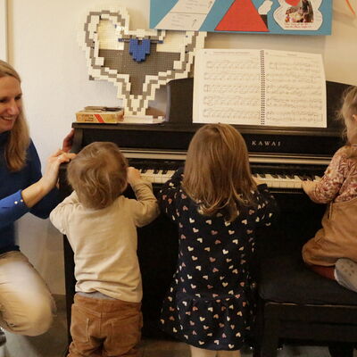 Tagesmutter übt mit den Kindern am Klavier