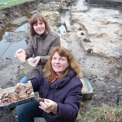Erste Kreisbeigeordnete Claudia Jäger und Dagmar Kroemer zeigen welche Fundstücke an der Niederungsburg in Hainhausen ausgegegraben wurden.