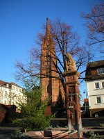 Vierröhrenbrunnen im Vordergrund und Stadtkirche Langen im Hintergrund.