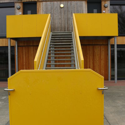In einem satten gelb setzt die Auentreppe ins Obergeschoss einen farblichen Kontrast zur Holzfassade.