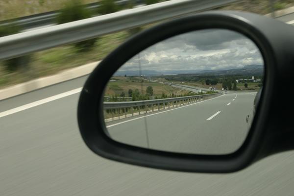 Blick in den Außenrückspiegel eines auf einer Autobahn fahrenden Autos.
