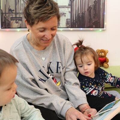 Tagesmutter schaut ein Bilderbuch mit den Kindern